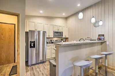 a kitchen with a stainless steel refrigerator and stools at Cozy Winter Park Condo, Walk to Ski Shuttle! in Winter Park