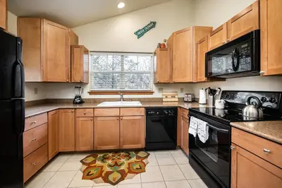 a kitchen with wooden cabinets and a black appliances at Sungate Condo: Nice Frisco Location in Frisco