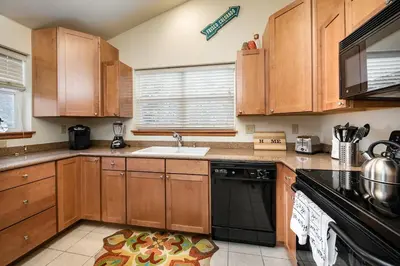 a kitchen with wooden cabinets and a black dishwasher at Sungate Condo: Nice Frisco Location in Frisco