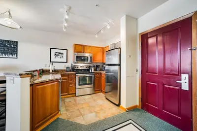a kitchen with wooden cabinets and a red door at Zephyr Mountain Ski-In Ski-Out Condo in Winter Park