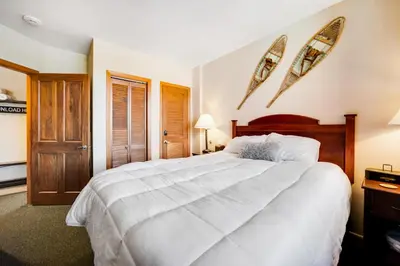 a bedroom with a large white bed and two surfboards on the wall at Zephyr Mountain Ski-In Ski-Out Condo in Winter Park