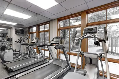 a gym with three tread machines and windows at Zephyr Mountain Ski-In Ski-Out Condo in Winter Park