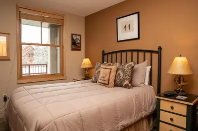 a bedroom with a bed with two lamps and a window at 8282 Silver Mill condo in Keystone