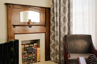 a room with a fireplace with a mirror and a chair at The Oxford Hotel in Denver
