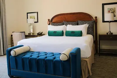 a bedroom with a large bed with a blue ottoman at The Oxford Hotel in Denver