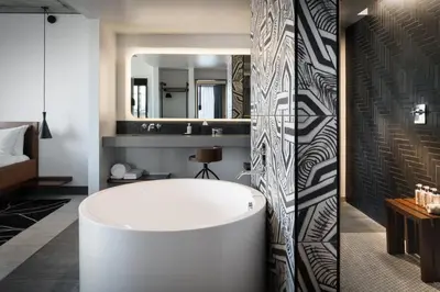 a bathroom with a white tub and a large mirror at The Maven Hotel at Dairy Block in Denver