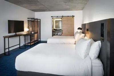 a hotel room with two beds and a flat screen tv at The Maven Hotel at Dairy Block in Denver
