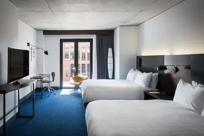 a hotel room with two beds and a television at The Maven Hotel at Dairy Block in Denver