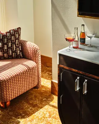 a living room with a chair and two glasses of wine at The Crawford Hotel in Denver