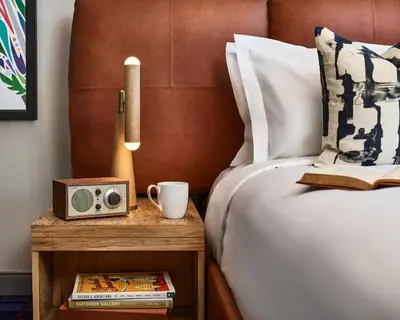a bed with a night stand with a radio and a cup at The Rally Hotel at McGregor Square in Denver