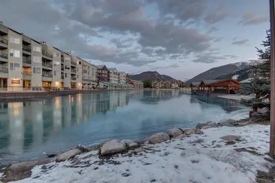 a view of a river with buildings and snow at Lakeside 1476 by SummitCove Lodging in Keystone