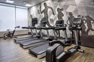 a gym with tread machines and a wall mural at Hyatt House Denver Aurora Anschutz Medical Campus in Aurora