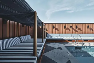 a pool with benches and a canopy next to a building at Clayton Hotel & Members Club in Denver