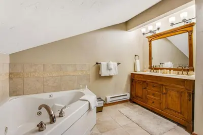 a bathroom with a tub and a sink and a mirror at Winter Park Place 14 in Winter Park