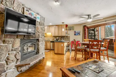 a living room with a stone fireplace with a television at Winter Park Place 14 in Winter Park
