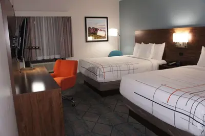 a hotel room with two beds and a chair at La Quinta Inn & Suites by Wyndham Littleton-Red Rocks in Littleton