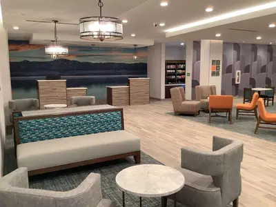 a waiting room with chairs and tables in a library at La Quinta Inn & Suites by Wyndham Littleton-Red Rocks in Littleton