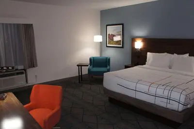 a hotel room with a bed and a chair at La Quinta Inn & Suites by Wyndham Littleton-Red Rocks in Littleton