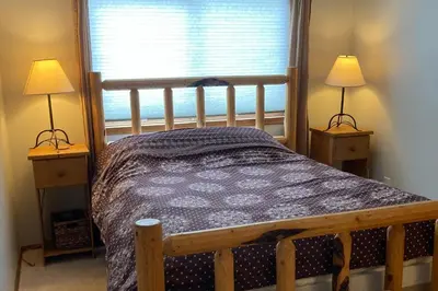 a bedroom with a wooden bed with two lamps at Twin Rivers 3 in Fraser