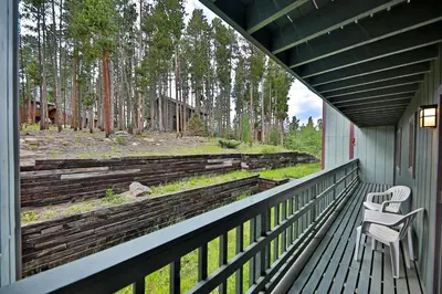 a porch with two chairs and a view of a forest at Timber Run Evergreen 9 in Winter Park