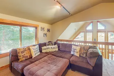 a living room with a brown leather couch andwindows at Spruce Chalet in Granby