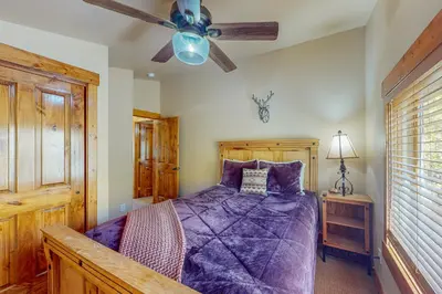 a bedroom with a purple bed with a ceiling fan at Spruce Chalet in Granby