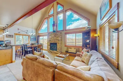 a living room with a large couch and a fireplace at Spruce Chalet in Granby