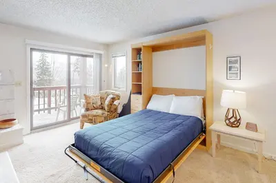 a bedroom with a bed and a chair and a window at Timber Run Vista 2 in Winter Park