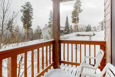 a balcony with two white chairs and snow on it at Timber Run Vista 2 in Winter Park