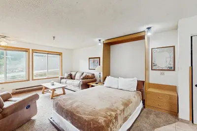 a bedroom with a bed and a living room with a couch at Snowblaze Condominiums E103 in Winter Park