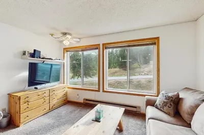 a living room with a couch and a tv and two windows at Snowblaze Condominiums E103 in Winter Park