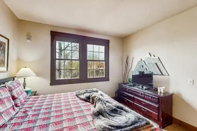a bedroom with a bed and a dresser and a window at Kicking Horse Lodges 4-205 in Granby