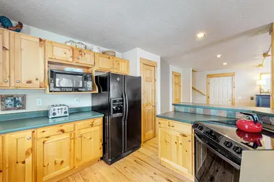 a kitchen with a black refrigerator and wooden cabinets at Sunset Chalet in Tabernash