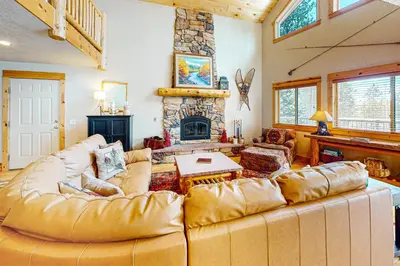 a living room with a large couch and a fireplace at Sunset Chalet in Tabernash