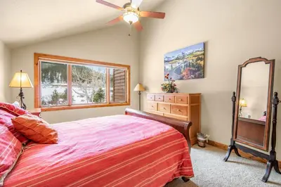 a bedroom with a bed and a dresser and a mirror at Tranquility On The River Three -- EV #6042 townhouse in Estes Park