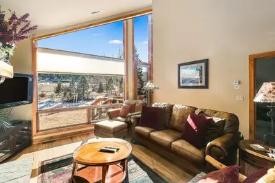 a living room with a couch and a large window at Tranquility On The River Three -- EV #6042 townhouse in Estes Park