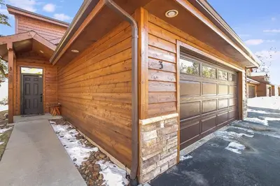 a wooden house with a fence and a garage at Tranquility On The River Three -- EV #6042 townhouse in Estes Park