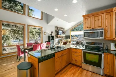 a kitchen with wooden cabinets and a table with chairs at Tranquility On The River Three -- EV #6042 townhouse in Estes Park