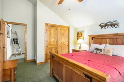 a bedroom with a large bed with a red bedspread at Tranquility On The River Four -- EV #6041 townhouse in Estes Park