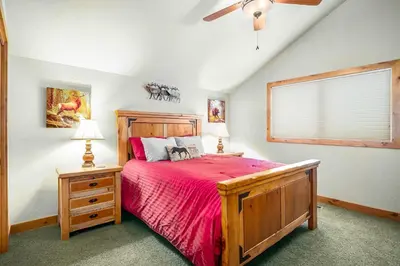 a bedroom with a wooden bed with a red bedspread at Tranquility On The River Four -- EV #6041 townhouse in Estes Park