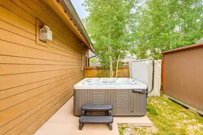 a backyard with a hot tub and a stool at Walk to Main St and Marina Grand Lake Cabin! in Grand Lake
