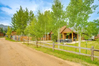 a house on a dirt road next to a fence at Walk to Main St and Marina Grand Lake Cabin! in Grand Lake
