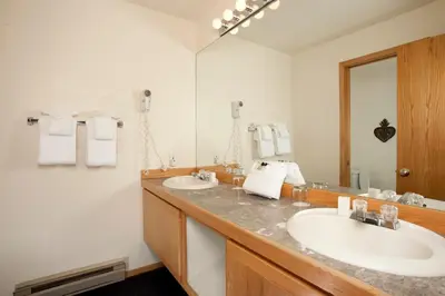 a bathroom with two sinks and a large mirror at River Run Village by Vail Resorts in Keystone