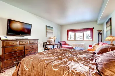 a bedroom with a large bed and a flat screen tv at Gateway Mountain Lodge, A Vail Resorts Property in Keystone