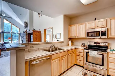 a kitchen with wooden cabinets and a sink at Gateway Mountain Lodge, A Vail Resorts Property in Keystone