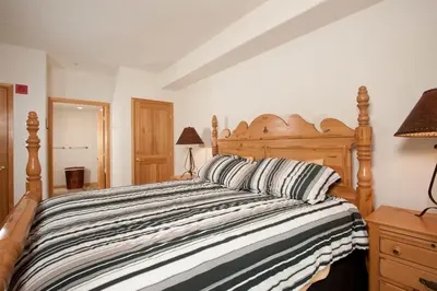 a bedroom with a large wooden bed with striped pillows at Gateway Mountain Lodge, A Vail Resorts Property in Keystone