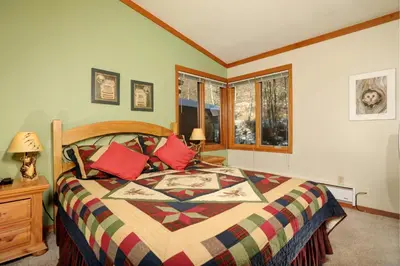 a bedroom with a large bed with red pillows at Aspen Ridge Condominiums by Vail Resorts in Keystone