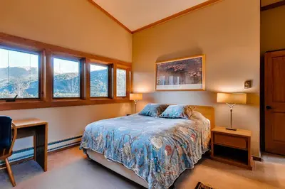 a bedroom with a bed and two tables and windows at Aspen Ridge Condominiums by Vail Resorts in Keystone