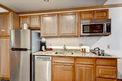 a kitchen with wooden cabinets and a stainless steel refrigerator at Mountain House, A Vail Resorts Property in Keystone