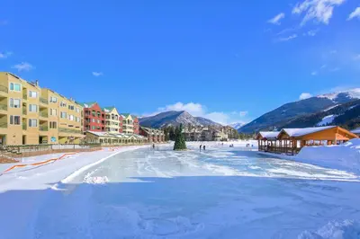 a street covered in snow with buildings and mountains at Lakeside Village by Vail Resorts in Keystone